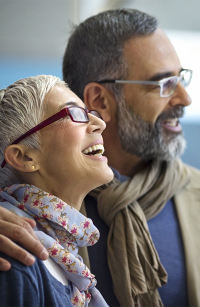 Closeup side view of a late 40's couple standing in front of eyeglasses store and making a choice for buying a new pair each. They are amazed with the selection offered and can't make up their mind.